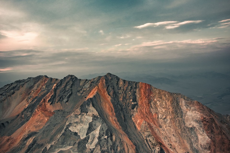 A rugged mountain range with distinct ridges and valleys under a cloudy sky.
