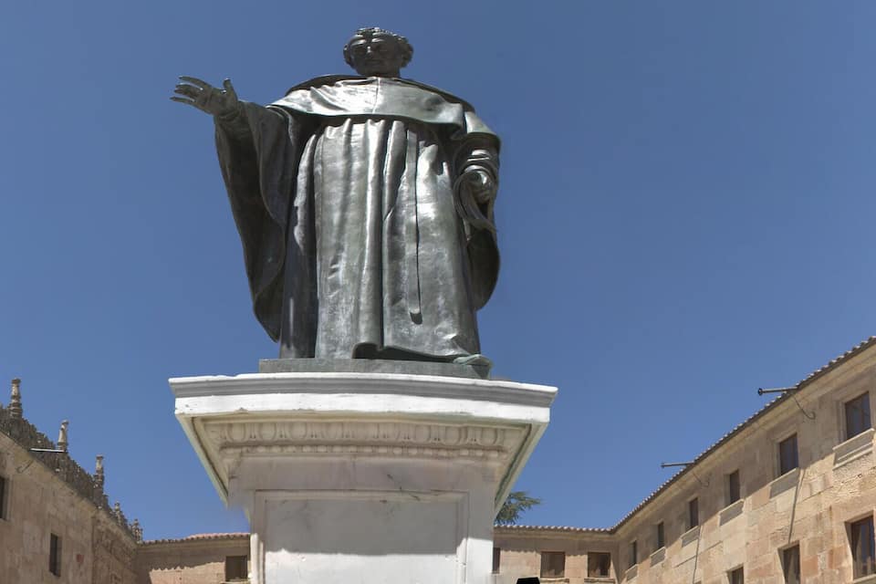 A statue in a plaza with ornate buildings on either side.