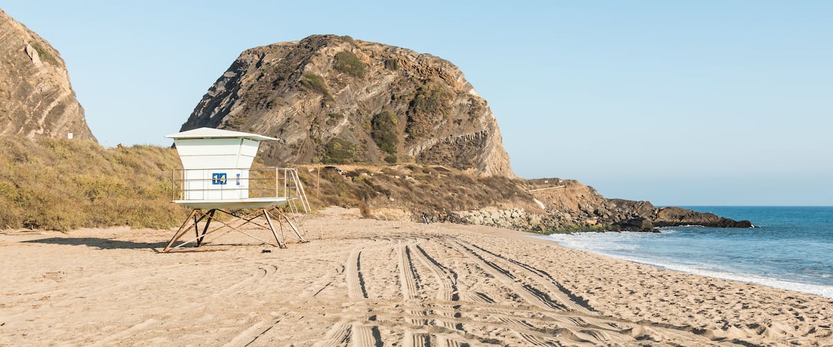 A lifeguard tower at Point Mugu State Park on the Pacific Coast Highway in Malibu, California with Mugu Rock in the background.