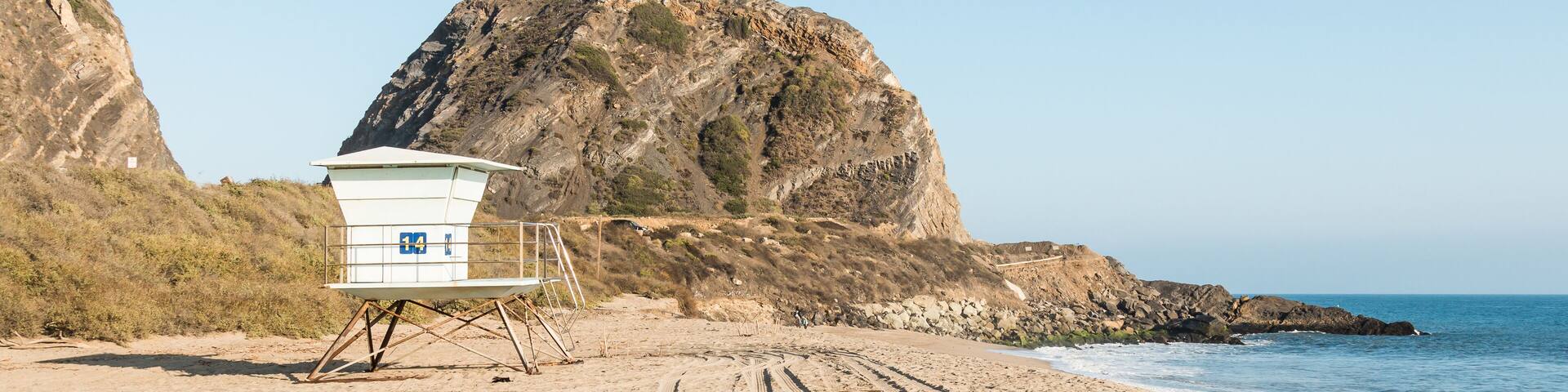 A lifeguard tower at Point Mugu State Park on the Pacific Coast Highway in Malibu, California with Mugu Rock in the background.