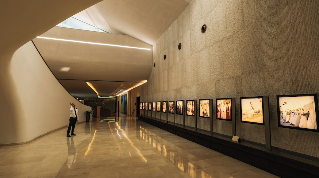 A modern interior with a long corridor lined with framed photographs on the wall.
