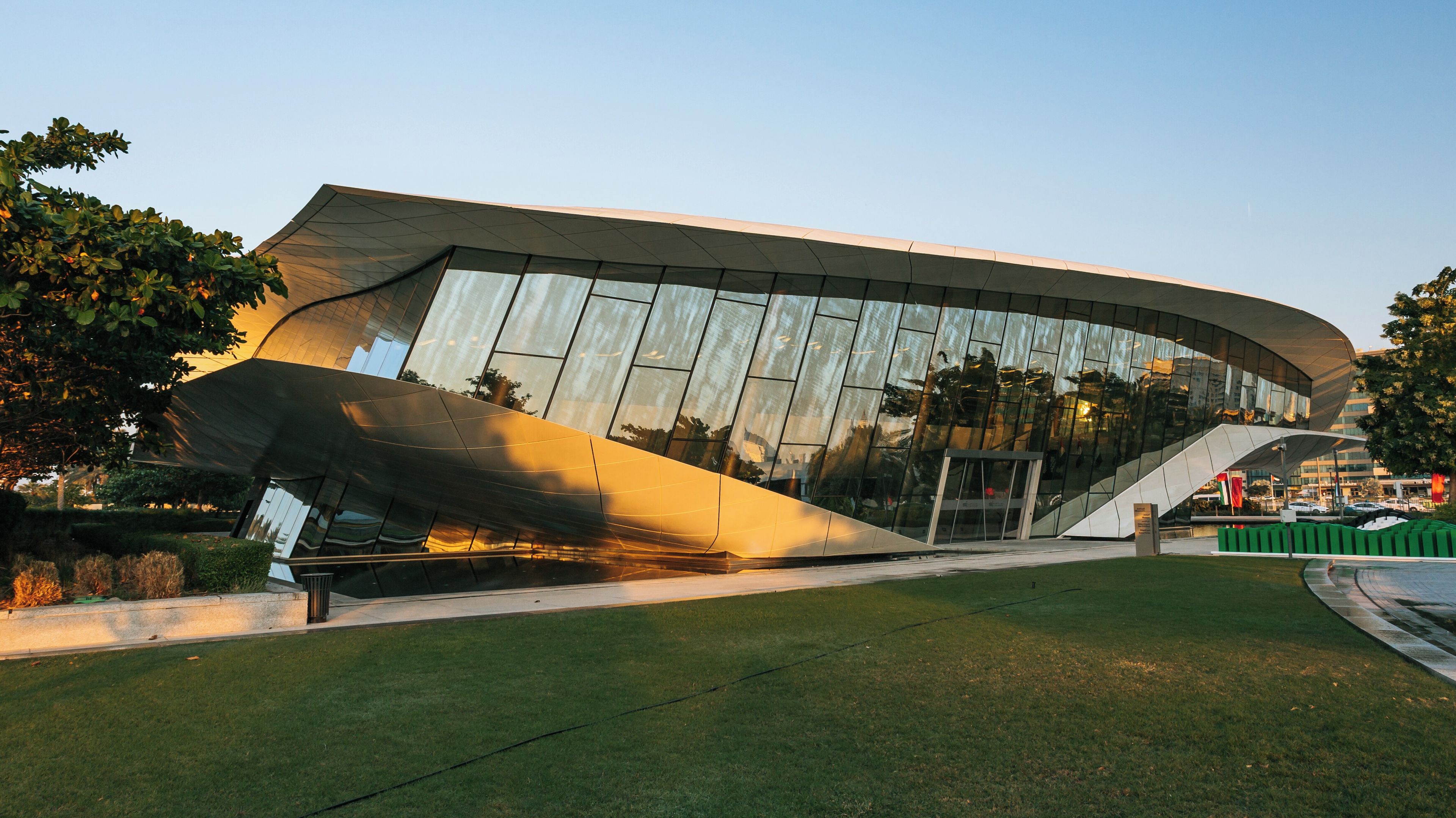 A modern architectural building with a curved roof and reflective glass facade.