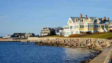 A waterfront property with a large house, a pier, and a rocky shoreline.