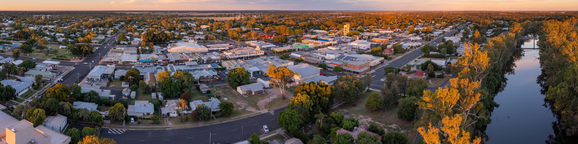 Aerial panorama of a river flowing alongside a regional town in late afternoon sunshine