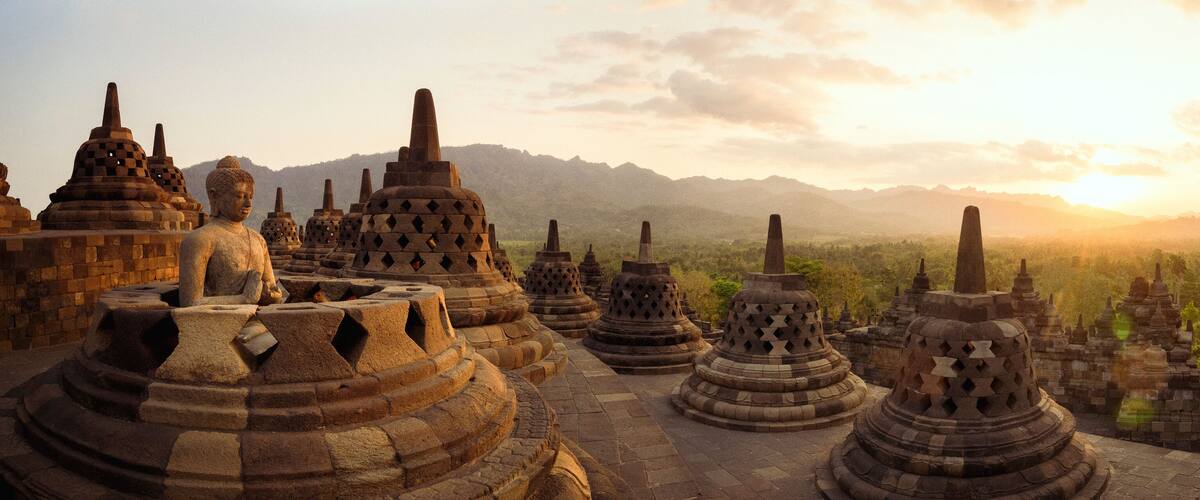 A temple complex with multiple stupa structures and a seated Buddha statue.