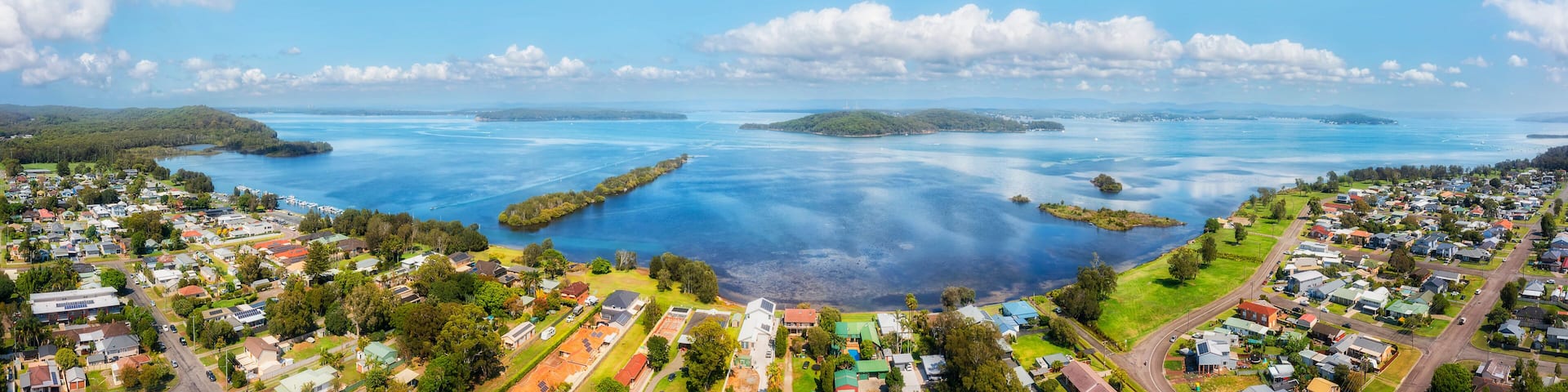 A coastal town with residential areas, a marina, and islands in the background.