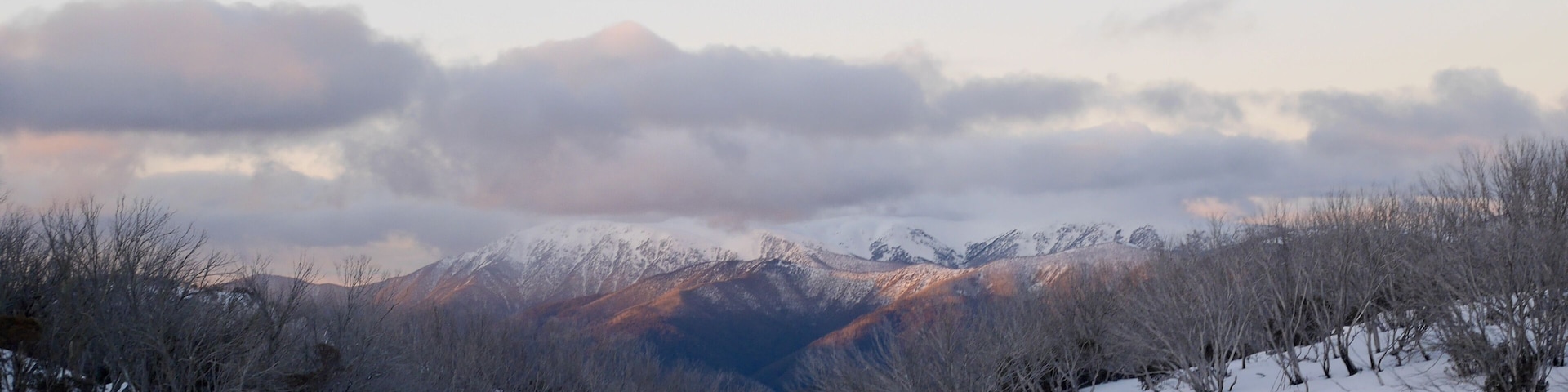 Beautiful snowy landscape at dusk with clouds and snow caped mountains in the background in the victorian alpine high country in Australia in winter