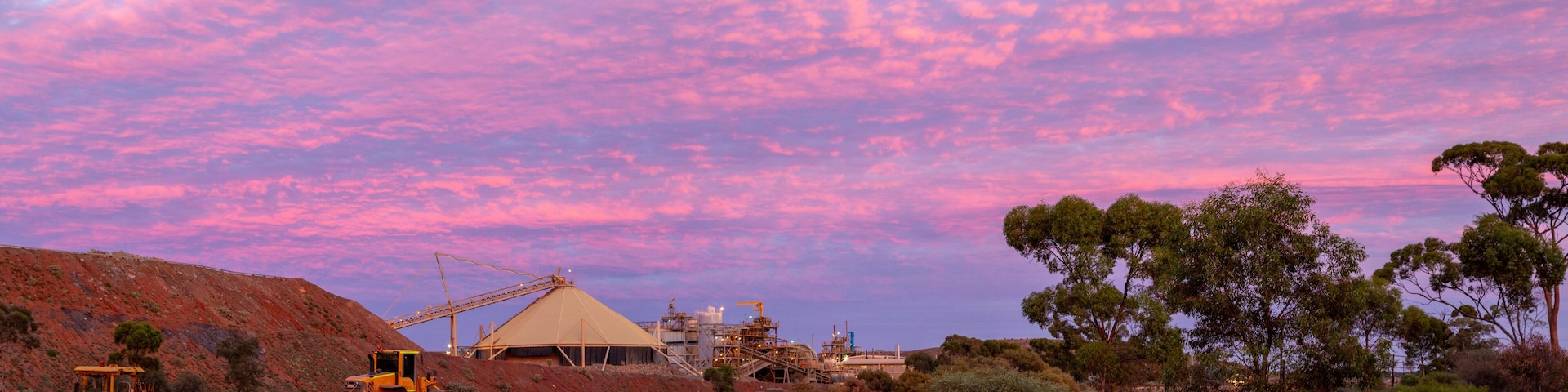 Sunset panorama of mine site and heavy machinery.