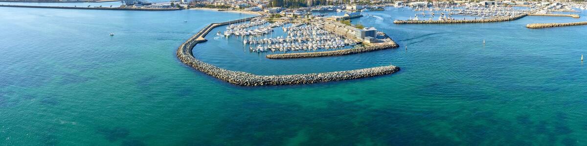 Panoramic shot of Fremantle's Challenger Harbour on a sunny day with boats, yachts. trees and groyne