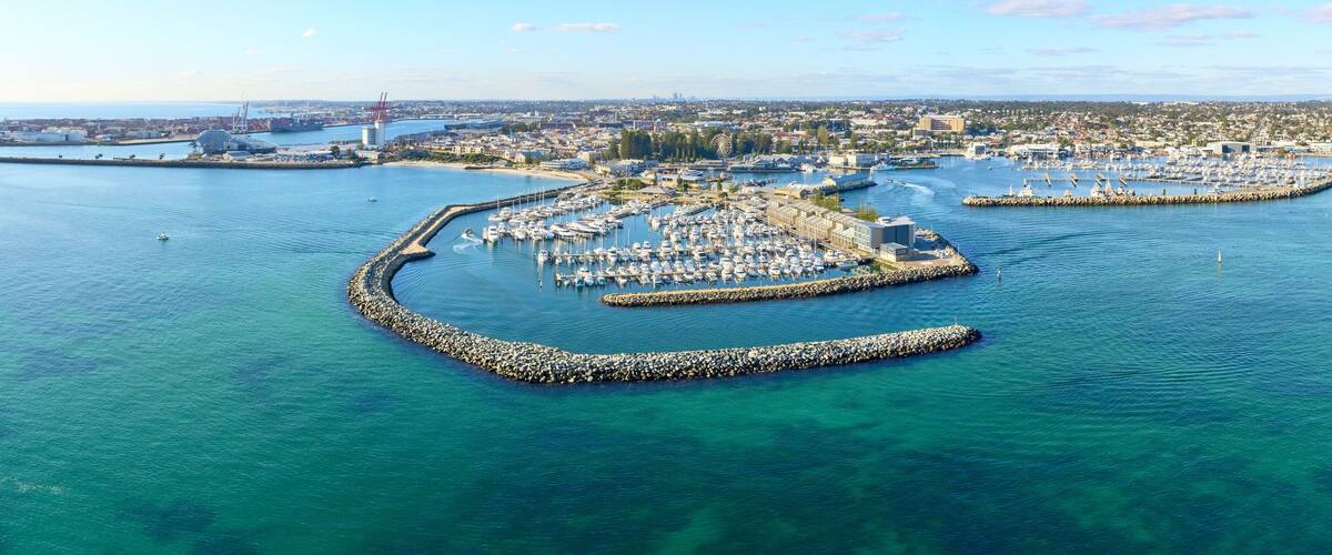 Panoramic shot of Fremantle's Challenger Harbour on a sunny day with boats, yachts. trees and groyne