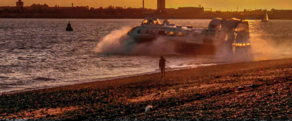 Regular hovercraft passenger service from Portsmouth to Ryde on the Isle of Wight. Sun setting over the former Haslar Royal Navy hospital in Gosport.