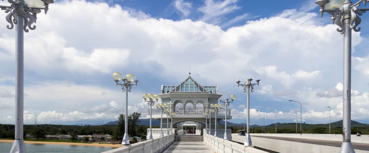 A bridge with a white railing, street lamps, and a gazebo-like structure in the distance.