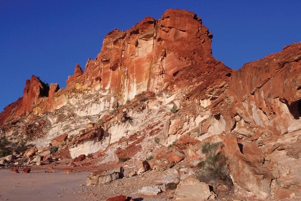 A rugged red rock formation with a clear blue sky.