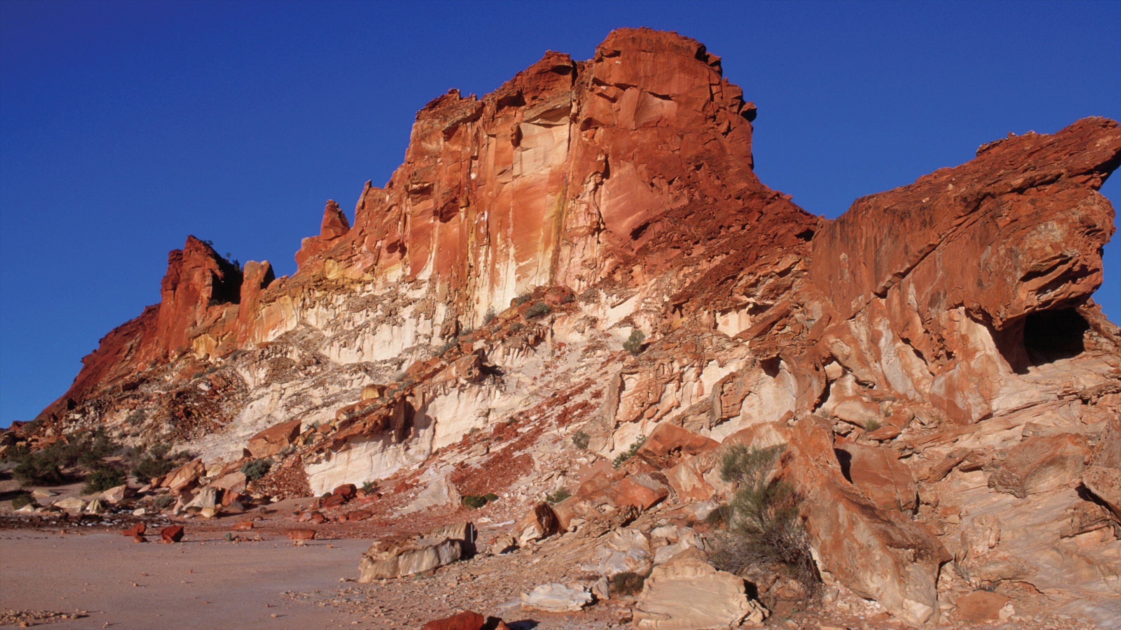 A rugged red rock formation with a clear blue sky.