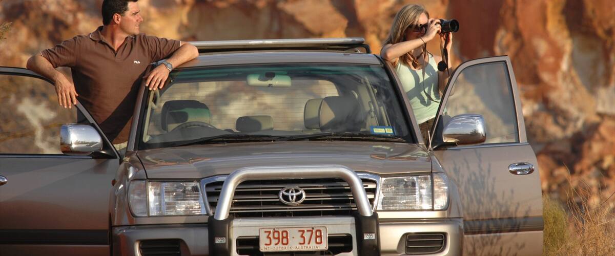 A Toyota SUV with a license plate reading "398 378" parked in a desert landscape with rocky formations in the background.