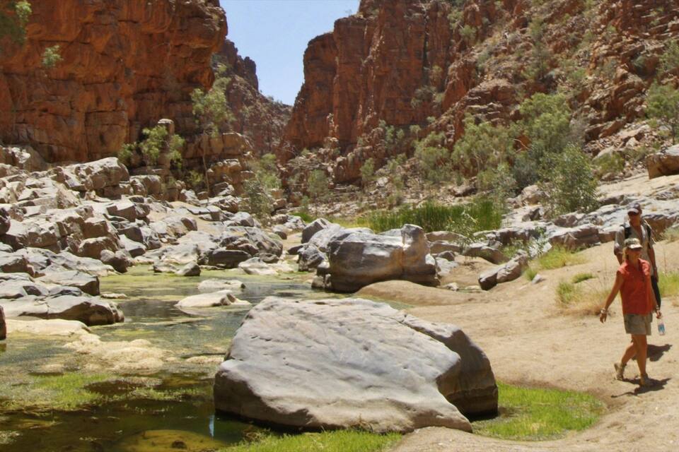 A canyon with a river, large boulders, and rocky cliffs.