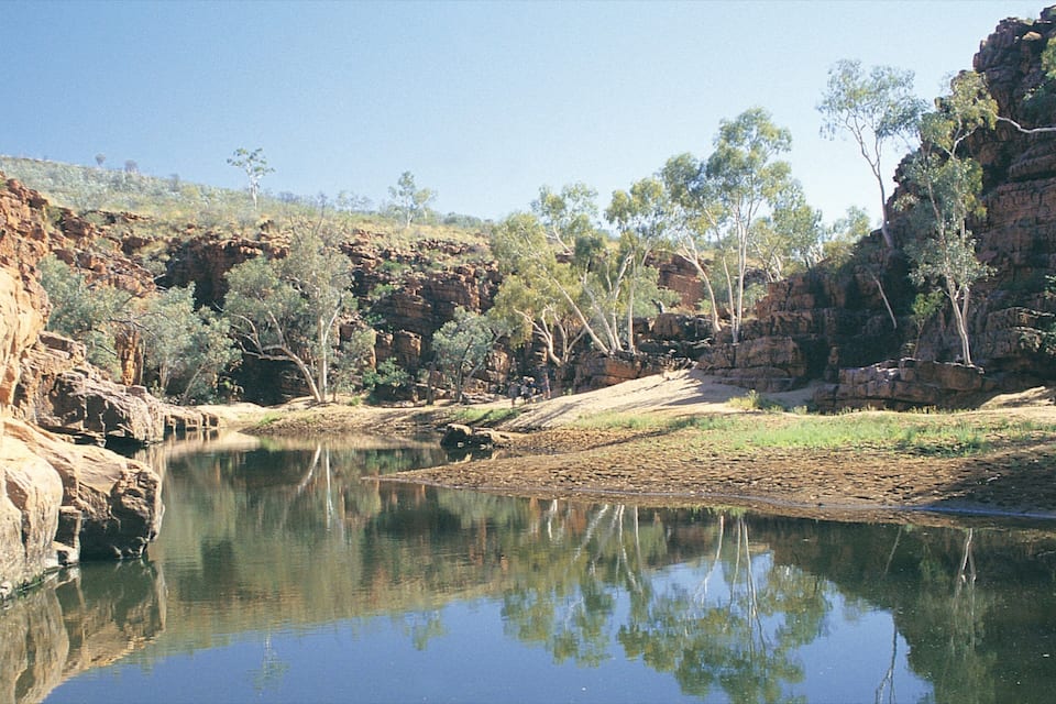 A river reflecting trees and rocky cliffs.