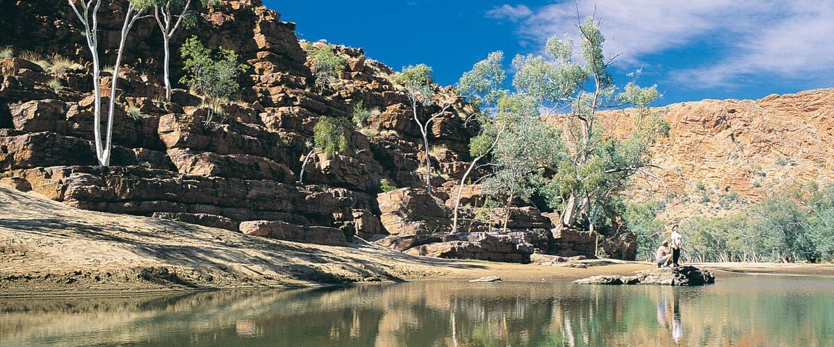 A river with rocky cliffs and sparse trees.