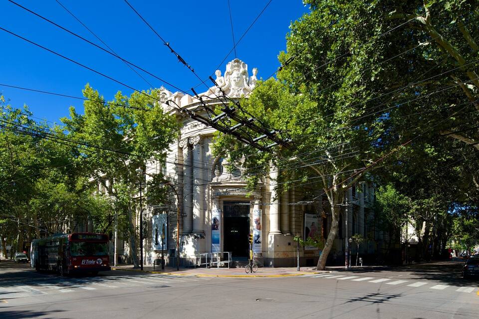 A street with a tram, trees, and a building with ornate architecture.