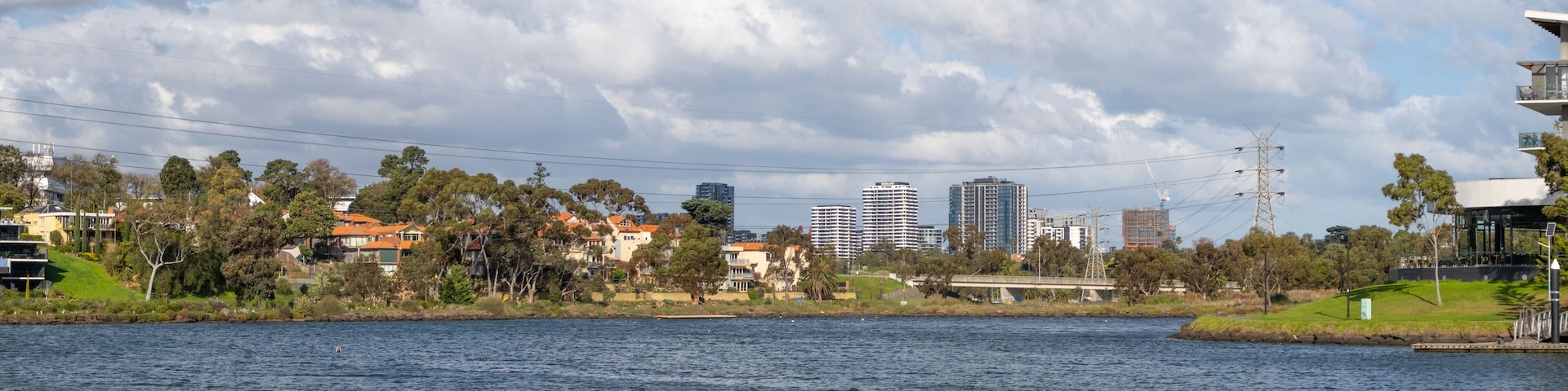 Panoramic background texture of urban landscape over Maribyrnong river with bridge, houses and apartment buildings in the distance. Panorama of waterfront scenery of Melbourne’s suburb, Australia.