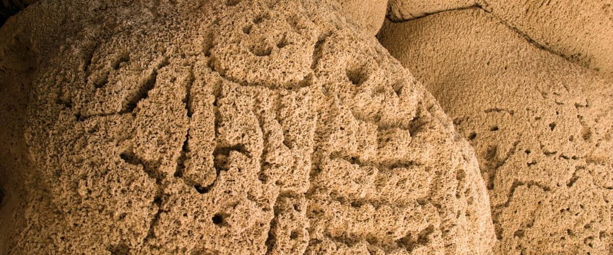 A close-up of a large, textured rock with carved patterns.
