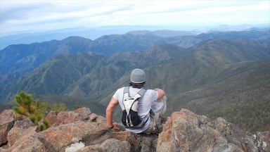 Un excursionista sentado sobre un saliente rocoso con vistas a un paisaje montañoso.