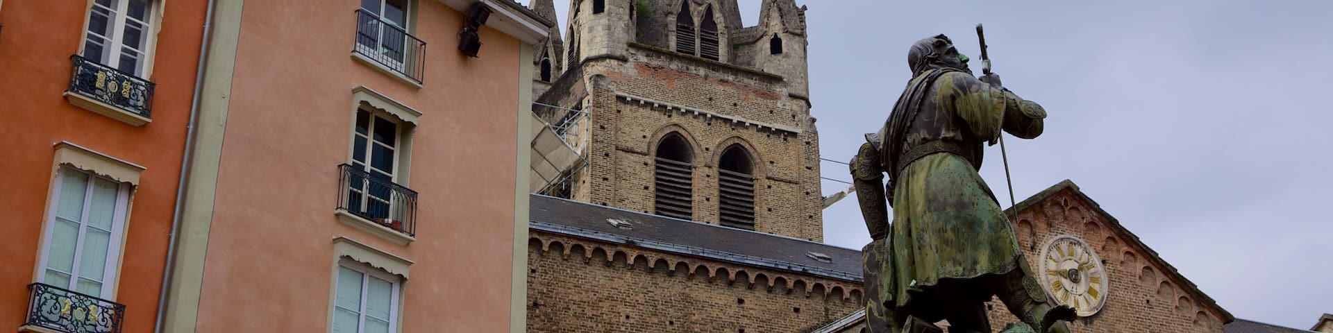 A church with a tall spire, a statue of a knight, and colorful buildings.