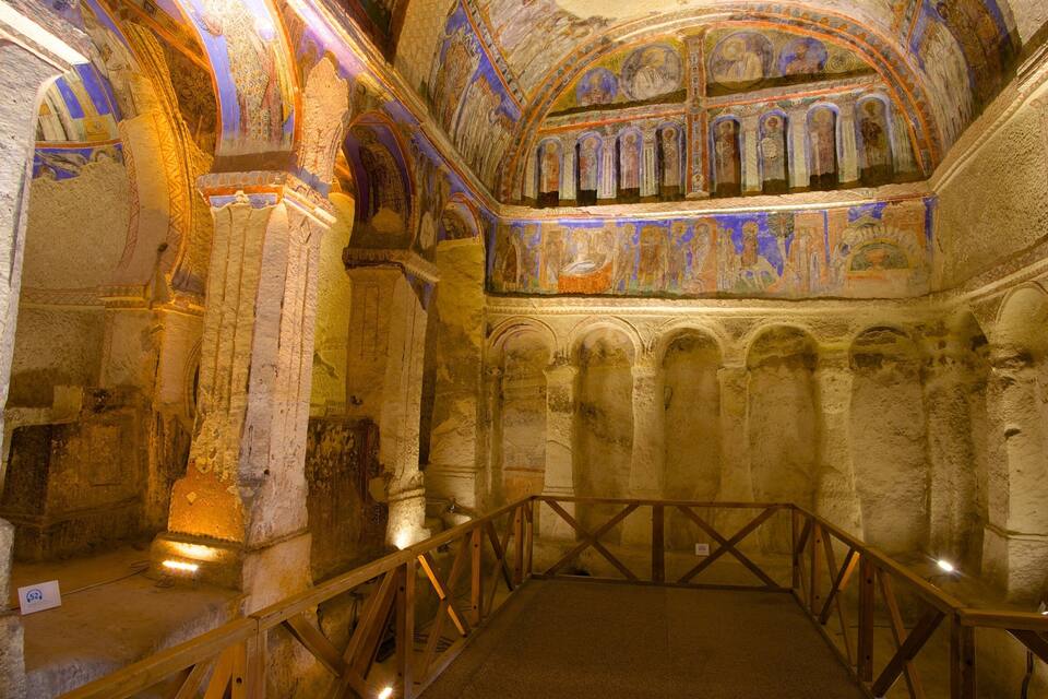 An ancient church interior with arched ceilings, columns, and a wooden railing.