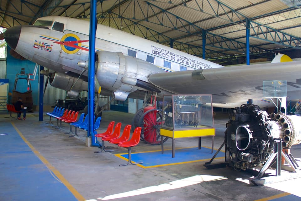 A vintage airplane on display with colorful chairs in front.