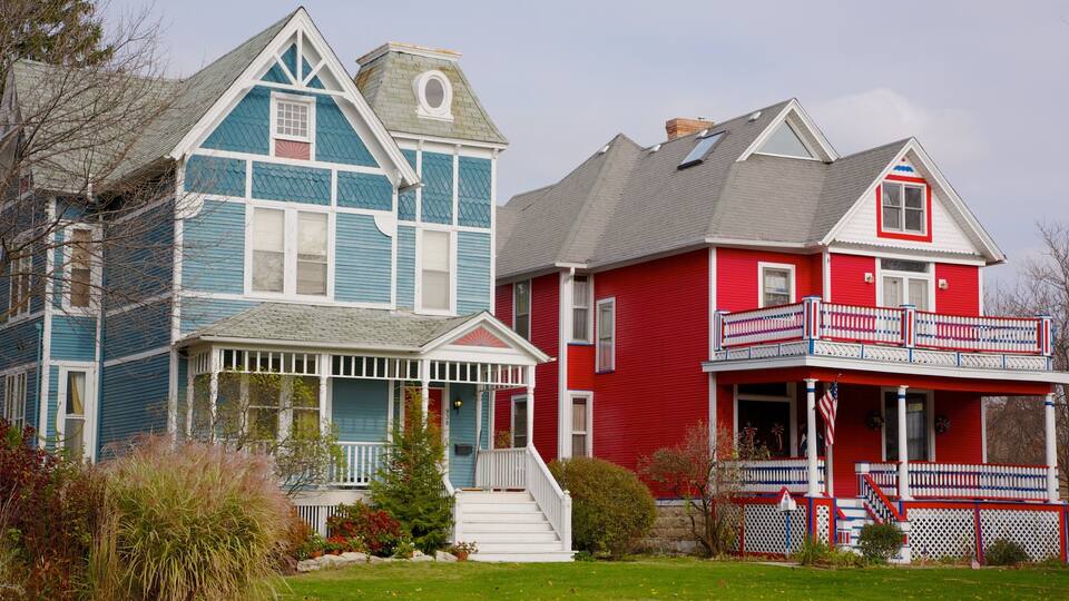 Two houses, one blue and one red, with a lawn and garden in front.