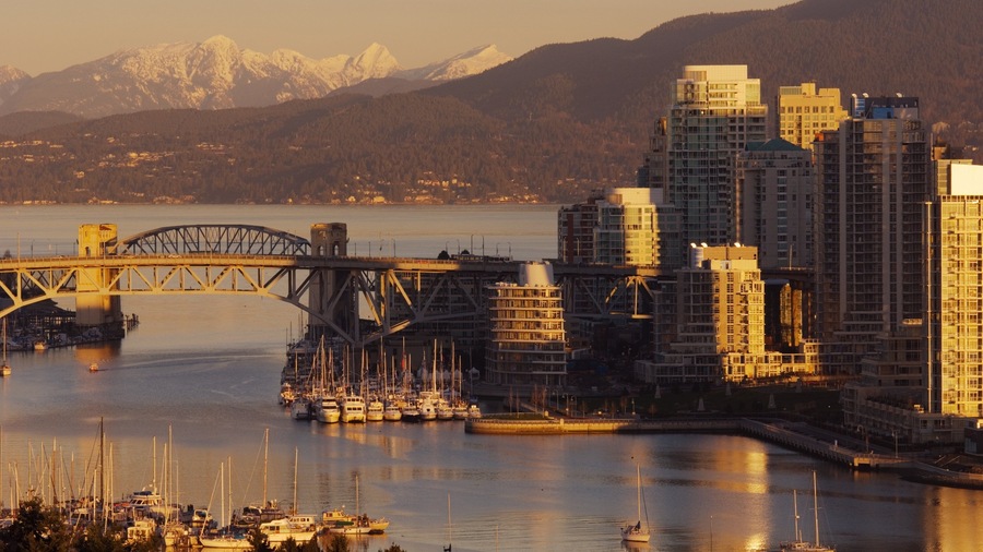 A cityscape with a bridge, buildings, and a mountainous backdrop.