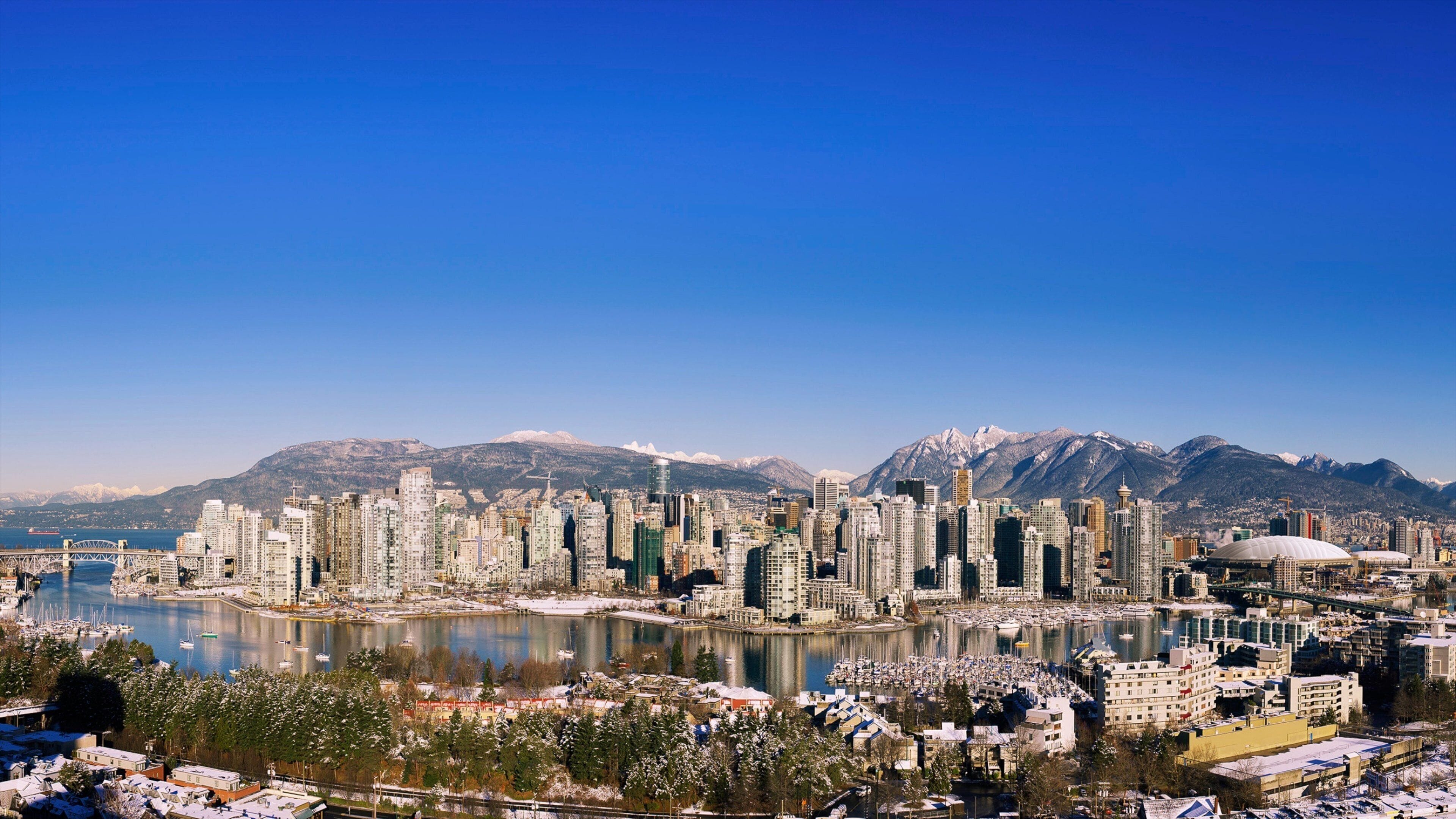 Vancouver's False Creek reflects a stunning urban skyline against a clear blue sky in winter
