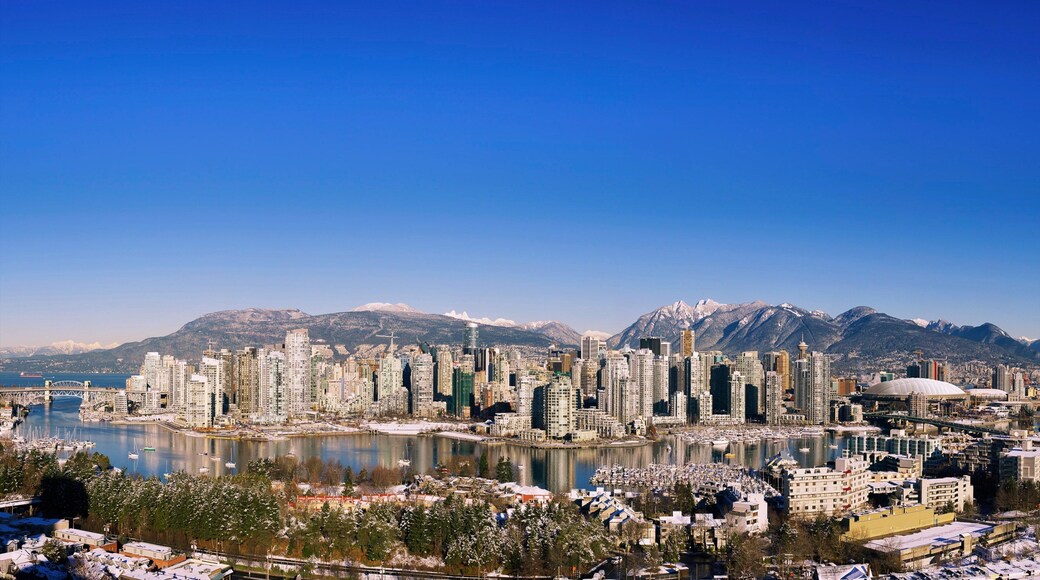 Vancouver's False Creek reflects a stunning urban skyline against a clear blue sky in winter