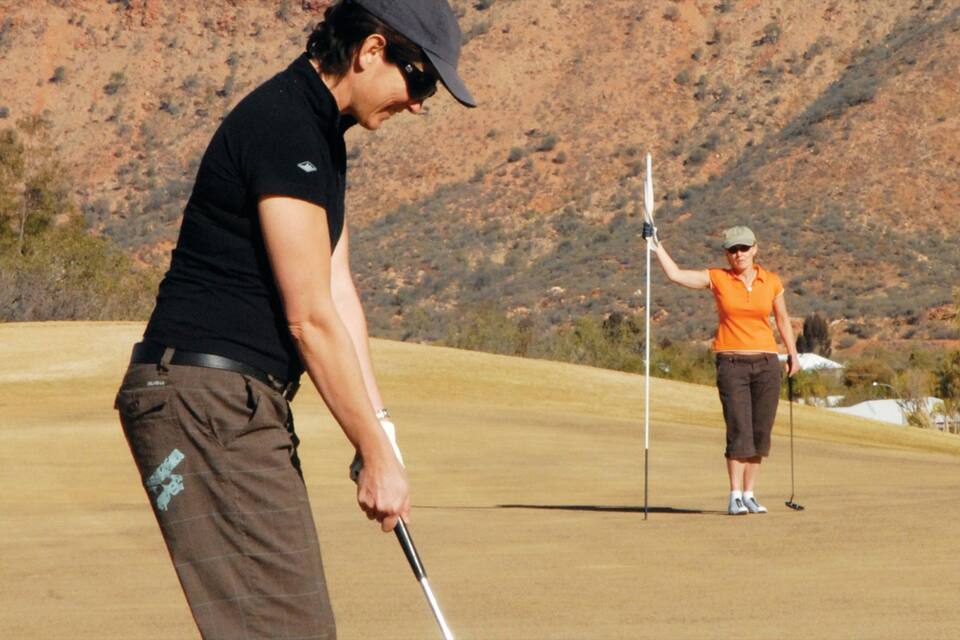 Um campo de golfe com paisagem desértica ao fundo.