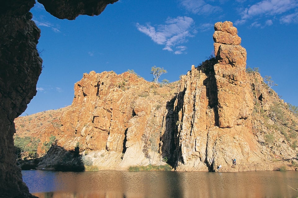 A rocky cliff with a prominent rock formation and a body of water at its base.