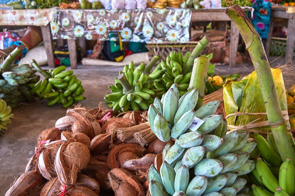 Um mercado com diversas frutas como bananas e cocos.