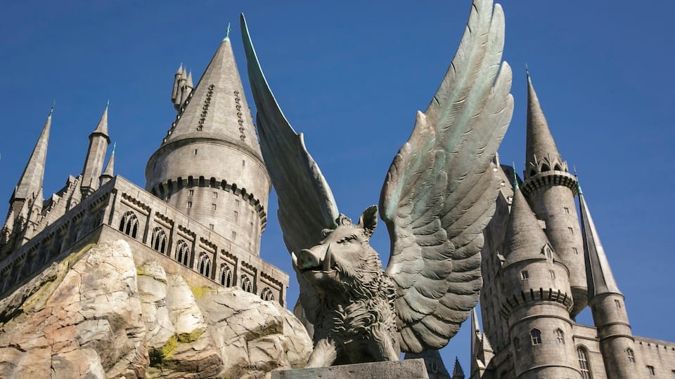 A castle with a large winged statue and multiple towers.
