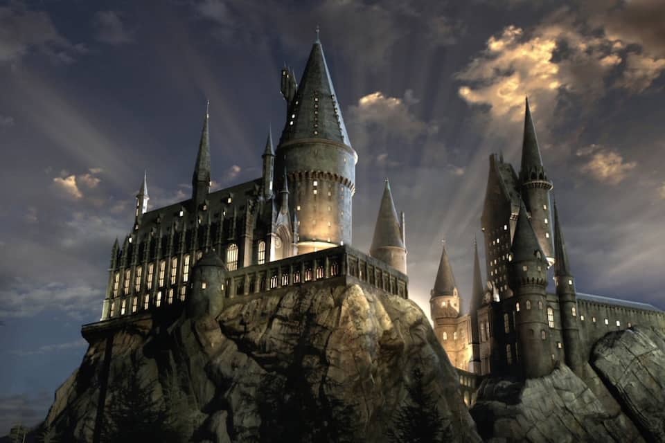 A large, multi-towered castle on a rocky outcrop with a cloudy sky.