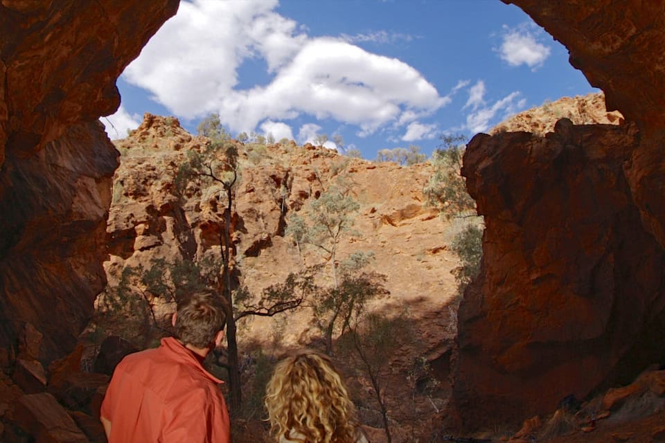 Eine Schlucht mit roten Felsformationen und vereinzelter Vegetation.