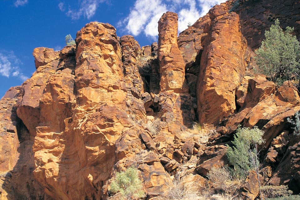A rugged rock formation with layered strata and sparse vegetation.
