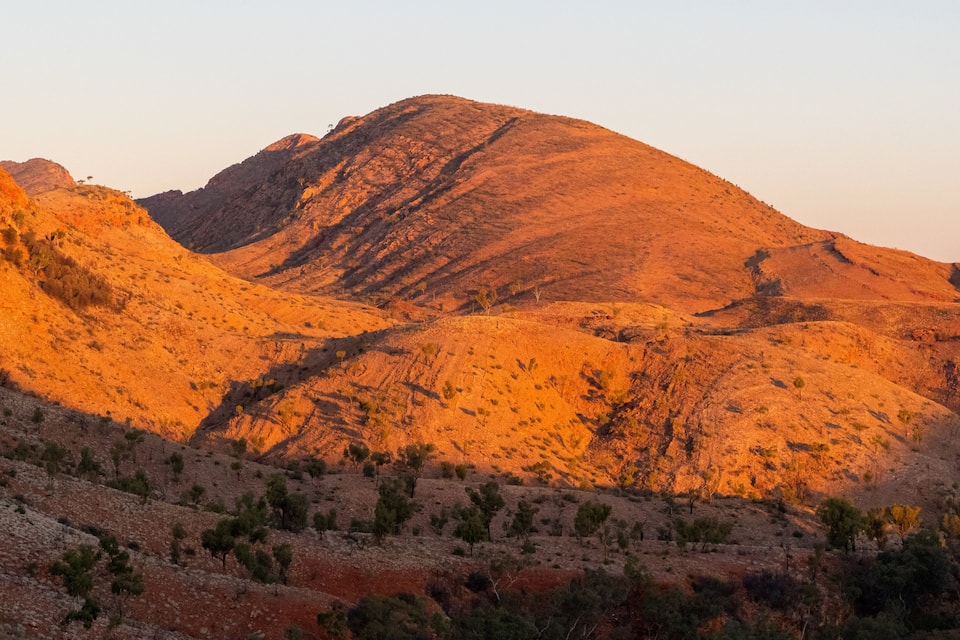 A rugged mountain landscape with sparse vegetation and a clear sky.