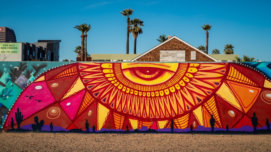 Roosevelt Row Arts District street art in Phoenix, Arizona, vibrant sun-and-eye mural with desert cacti under blue sky.