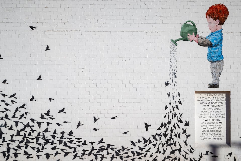 A mural of a boy watering birds, with a quote about life judgment.