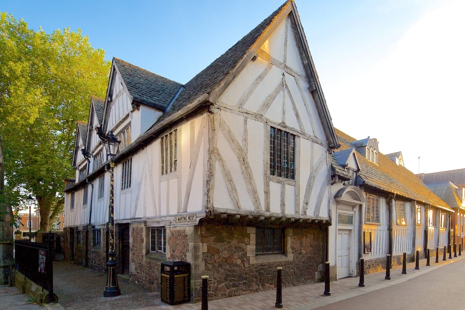 A historic half-timbered building with a stone base, a sign reading "S. MARTIN WEST," and a cobblestone street.