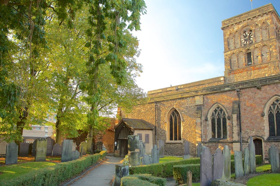 A church with a clock tower, stone walls, and a cemetery with headstones.