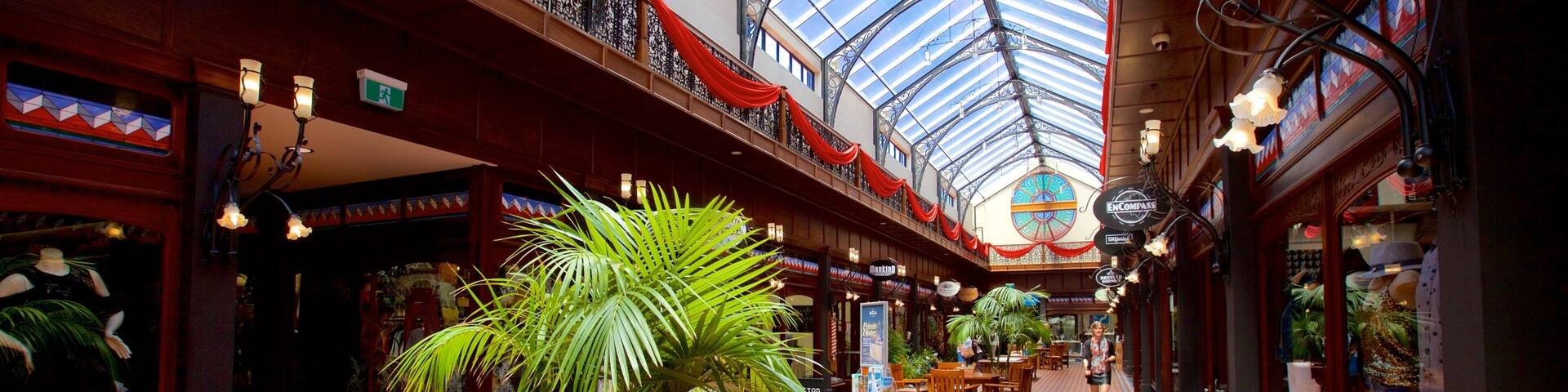 An indoor shopping mall with a high ceiling, patterned floor, and various shops.