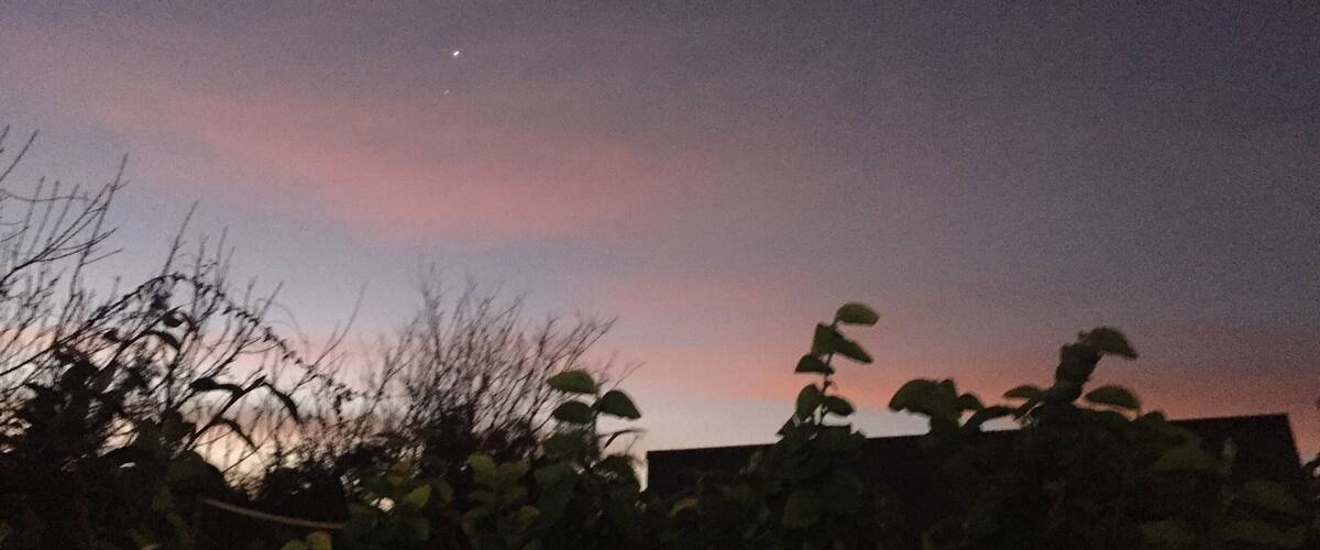A twilight sky with a visible moon and a pinkish hue near the horizon.