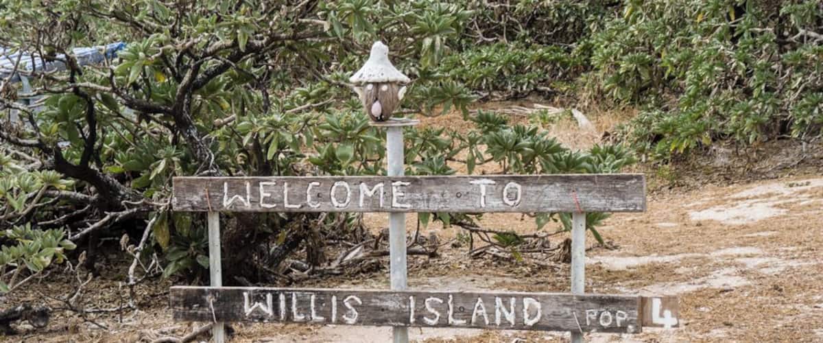 A wooden signpost with 'WELCOME TO WILLIS ISLAND' and a lamp post.