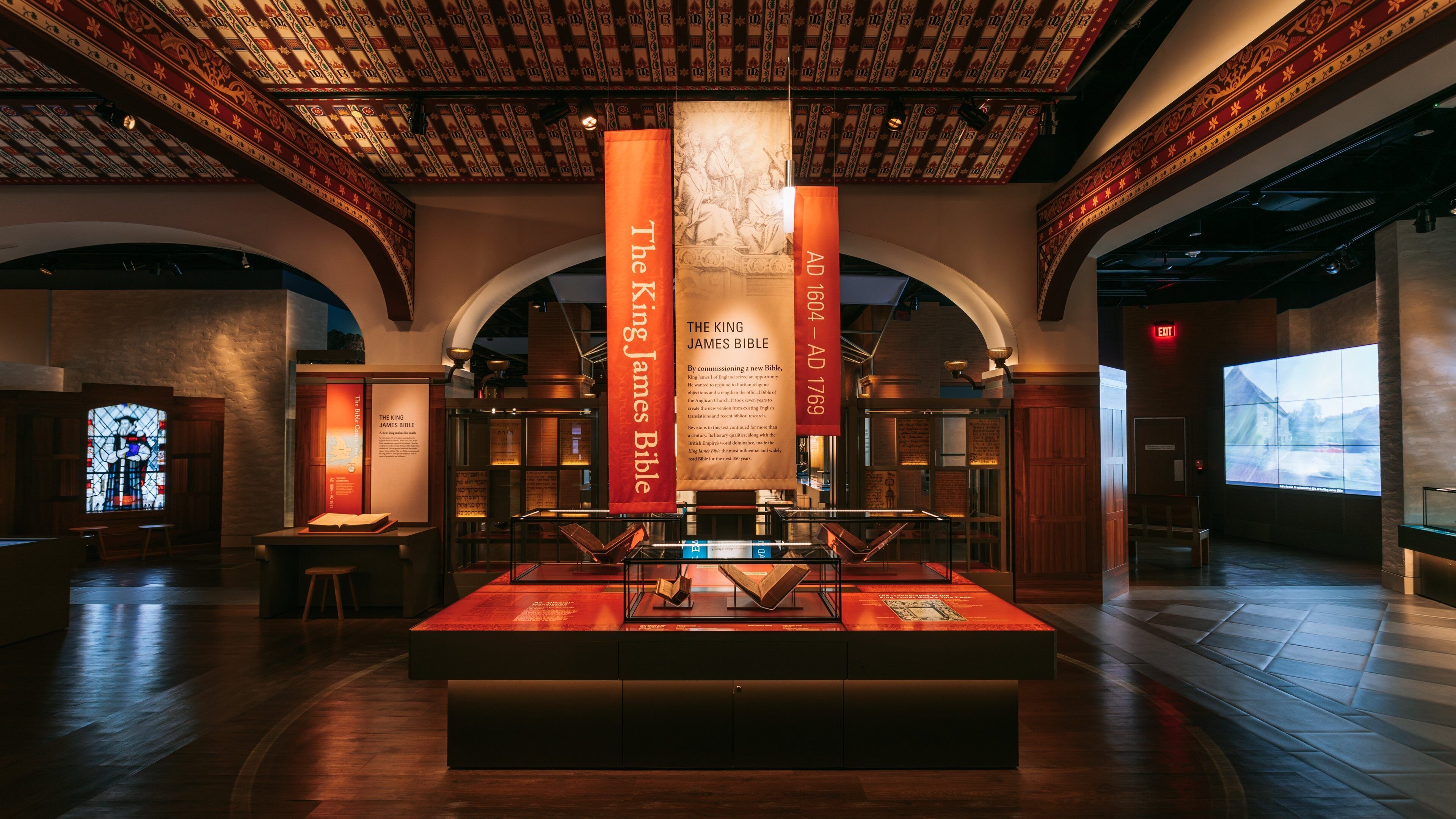 A museum interior with a display case containing the King James Bible, surrounded by informational panels and banners.