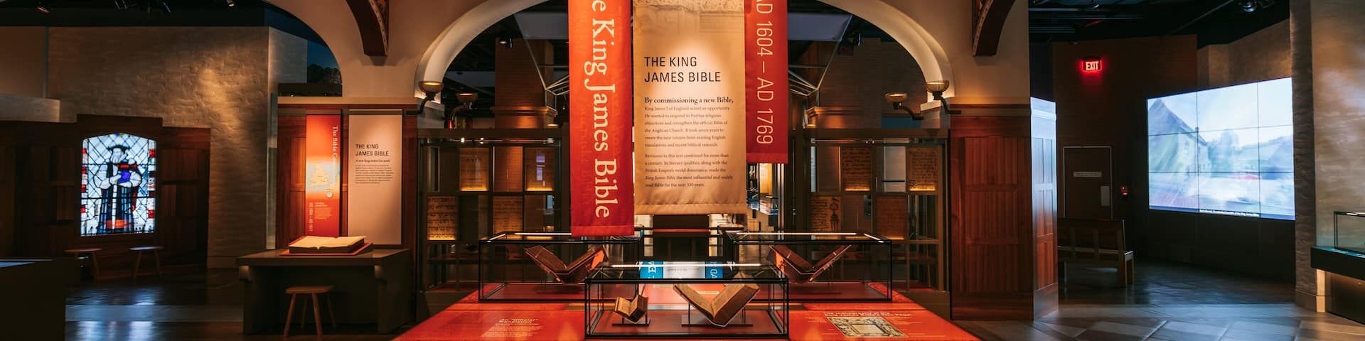 A museum interior with a display case containing the King James Bible, surrounded by informational panels and banners.